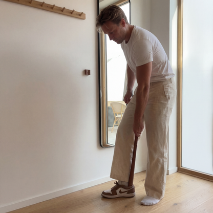 Man trekt rechtop staand zijn schoen aan met de schoenlepel