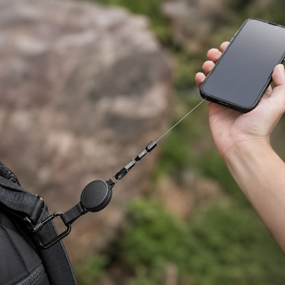 Belay anti-val telefoonkoord in gebruik - telefoon veilig aan het uitgerekte koord boven de rotsen