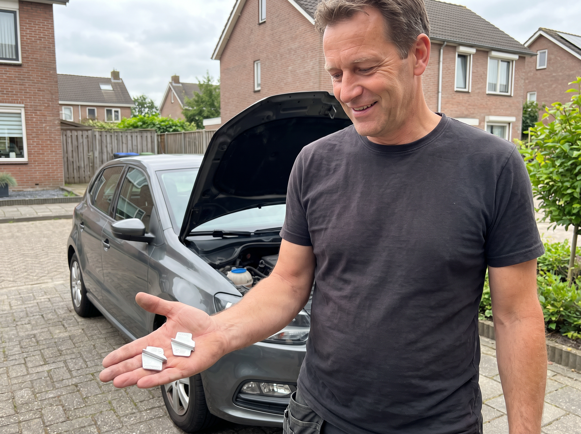 Man bij zijn auto op de oprit met de Volano montageset in zijn hand