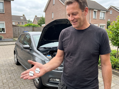 Man bij zijn auto op de oprit met de Volano montageset in zijn hand