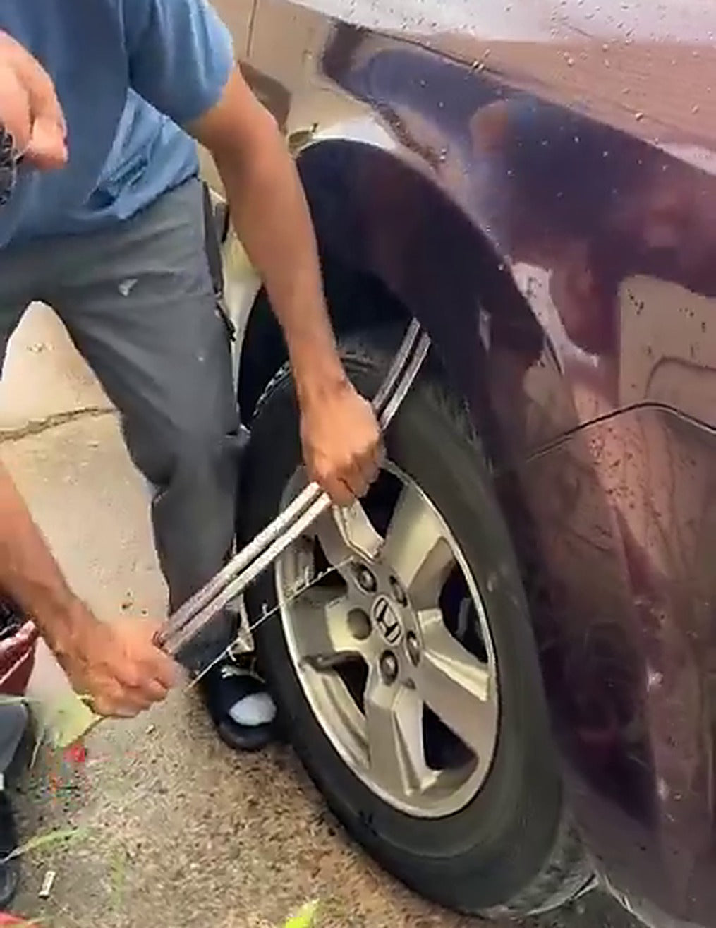 Man werkt met de Levar staaf aan de wielkastrand van zijn auto op de oprit