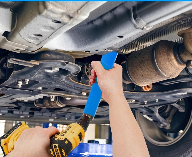 Torvex draait een bout los onder de auto, tussen uitlaat en hitteschild